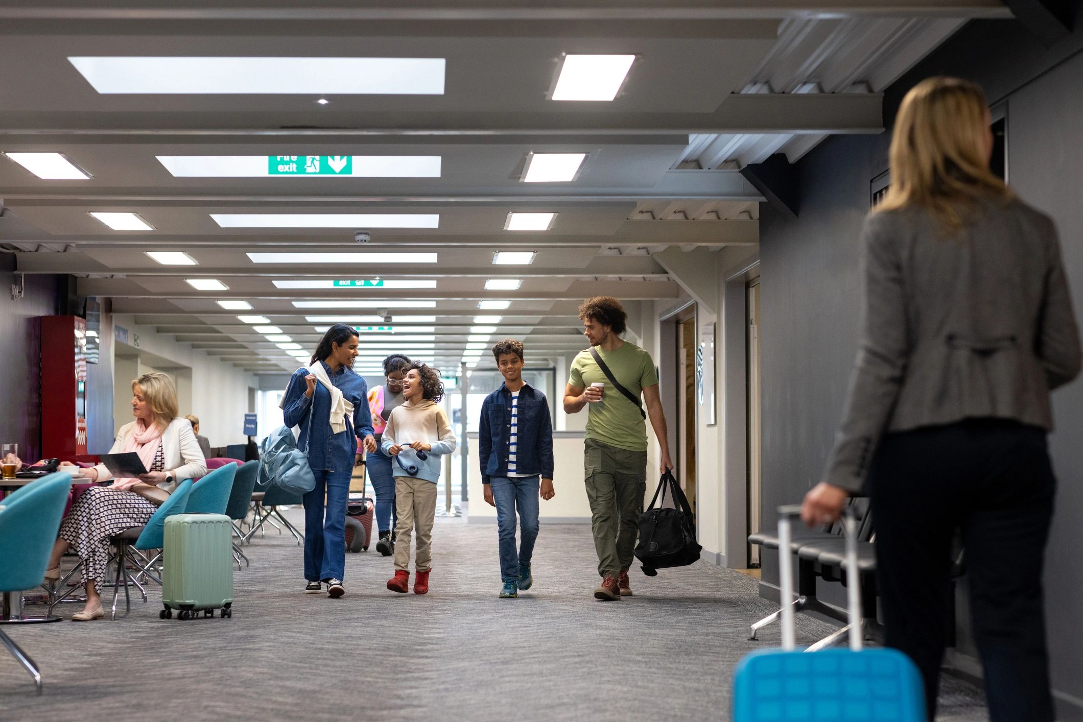 Family walking through an airport terminal with luggage while planning a protected holiday