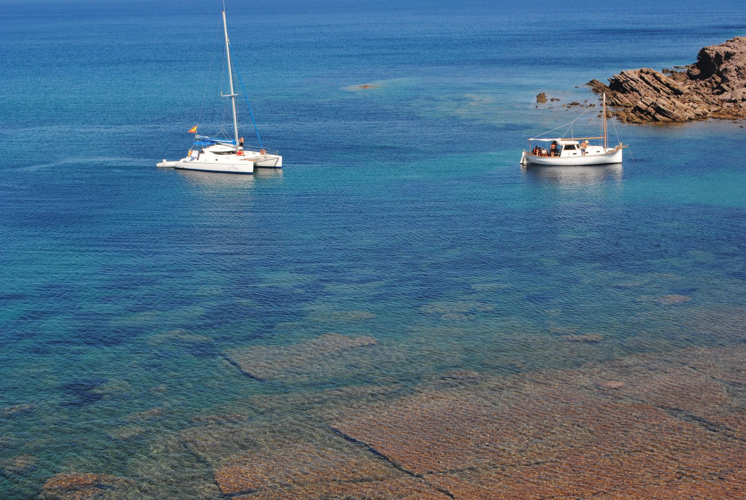 Turquoise Menorca bay with anchored sailboats