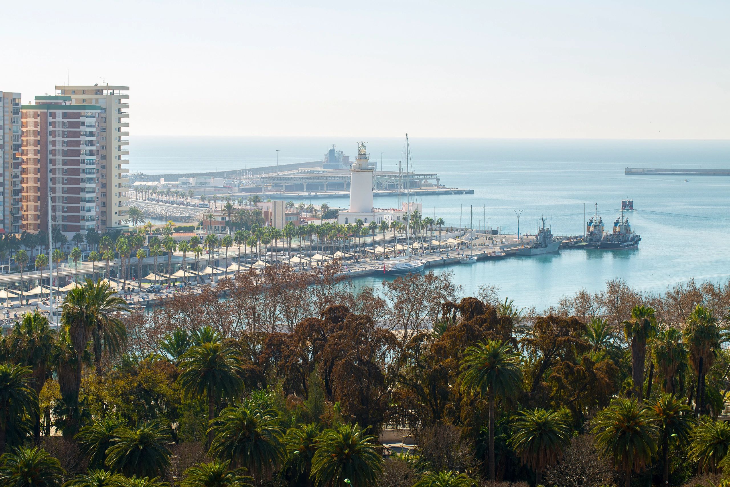 Port of Malaga waterfront and La Farola lighthouse at sunset