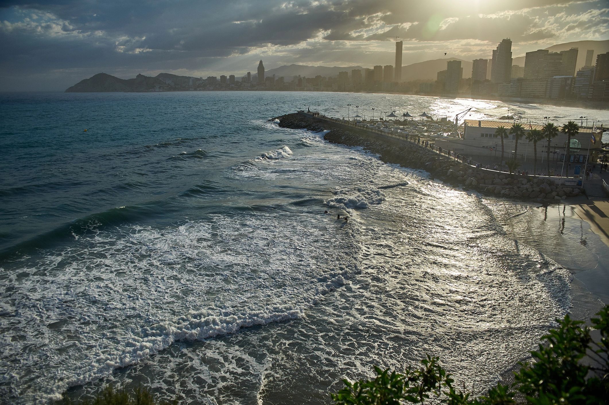 Benidorm coastline at sunset with waves and city skyline in the distance