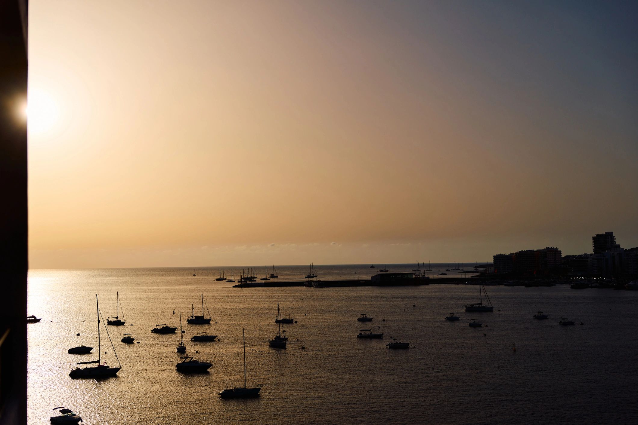 Golden sunset light reflecting on harbour and boats in Ibiza